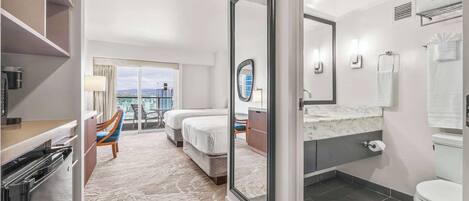 A modern hotel room with a balcony, a large mirror, a bathroom with a toilet and sink, and a dining area with a table and chairs.