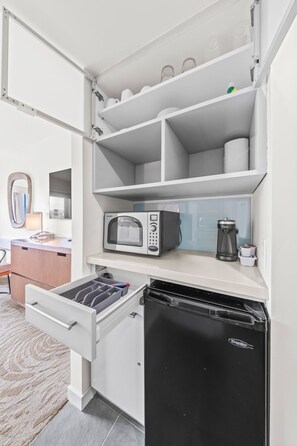 A compact kitchen with a built-in microwave, coffee maker, and a black refrigerator. - Newly Renovated Ala Moana with Balcony (Honolulu)