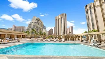 A hotel pool area with a clear view of tall buildings in the background.