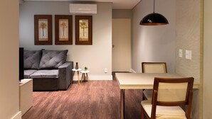 A modern living room with a sofa, a dining table with chairs, and framed artwork on the wall.