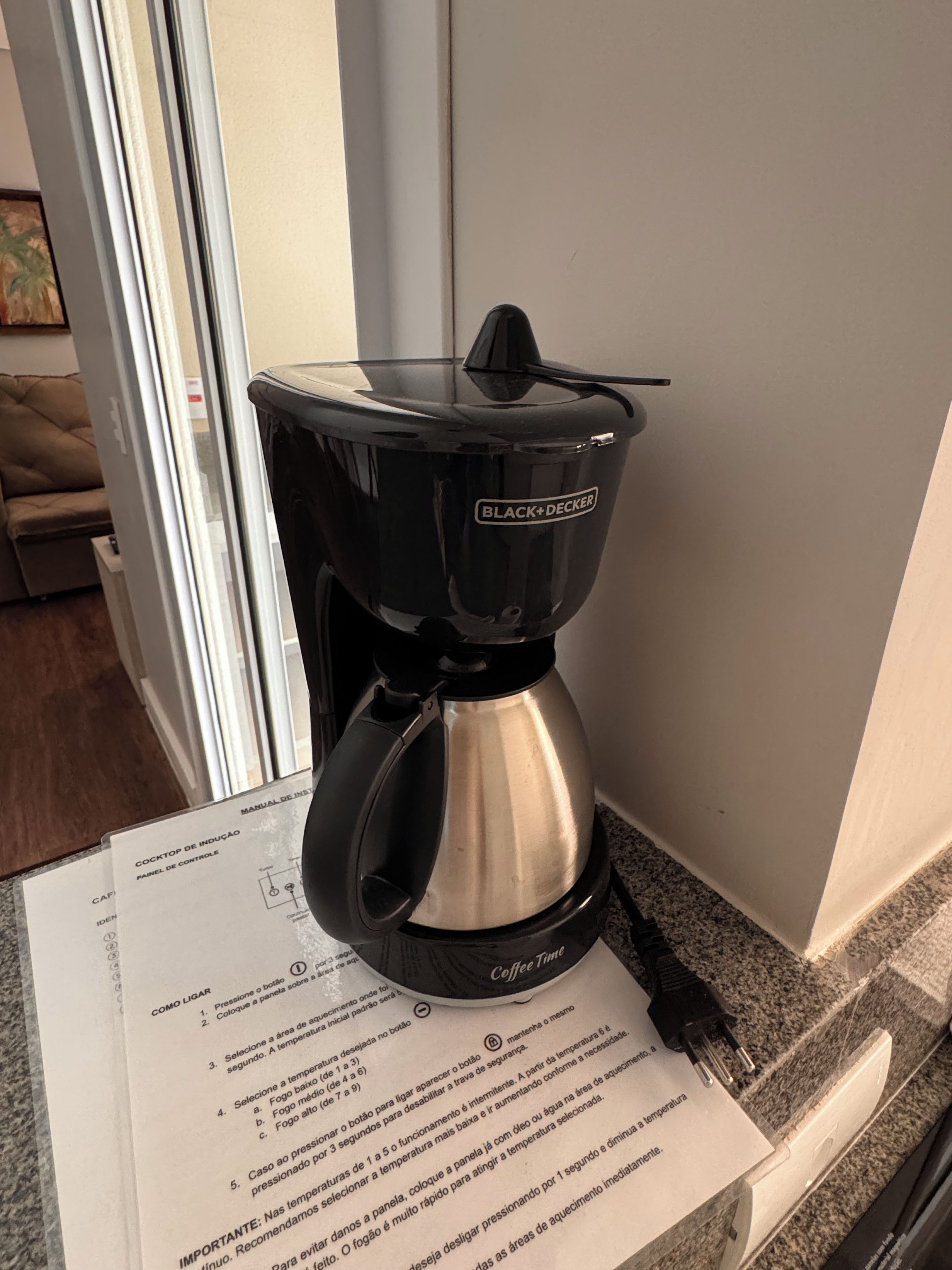 En kaffemaskine på en bordplade med en brugsanvisning ved siden af.