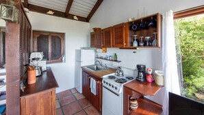 Een kleine keuken met houten kastjes, een fornuis en een spoelbak.