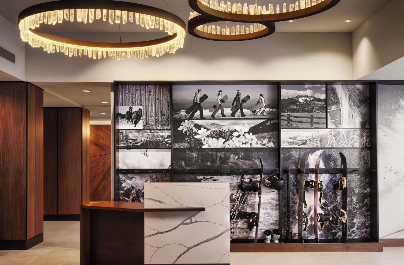 A lobby with a large wall of black and white photographs, wooden paneling, and a marble reception desk.