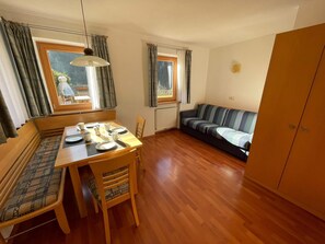 Ein gemütlicher Wohnbereich mit einem Holzespeisetisch für vier Personen, einer Couch und einem Kleiderschrank.