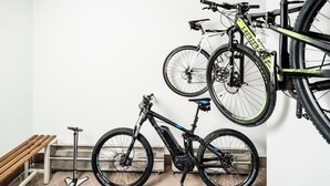 A room with a bicycle rack holding two bicycles, a bench, and a scooter. - Apartments Hetty (Santa Cristina Valgardena)