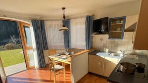 A kitchen with a dining area, a sink, and a window with curtains. - Apartments Hetty (Santa Cristina Valgardena)