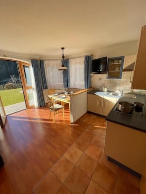 A kitchen with a dining area, a sink, and a window with curtains. - Apartments Hetty (Santa Cristina Valgardena)
