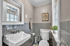 Ein Badezimmer mit Waschbecken, Toilette und einem Fenster mit Jalousien.