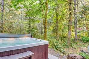 Ein Whirlpool inmitten von Bäumen mit einer hölzernen Bank und einem Felsen in der Nähe.