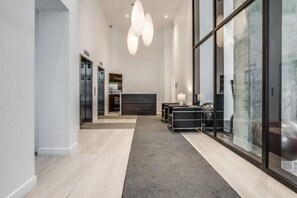 A modern hotel lobby with a reception desk, a seating area, and a glass wall. - CONDO DOWNTOWN MONTREAL - GRIFFINTOWN W (Montréal)