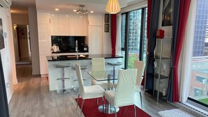 Een moderne keuken met een glazen eiland, witte stoelen en een rood tapijt.