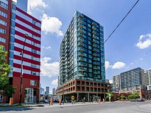 A multi-story building with a glass facade and a red and white striped building adjacent to it. - CONDO DOWNTOWN MONTREAL - GRIFFINTOWN W (Montréal)