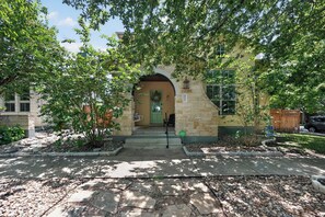 A residential building with a stone facade, a green door, and a porch area.