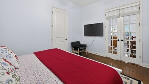 Une chambre à coucher avec un lit, un téléviseur fixé au mur et un ventilateur de plafond.