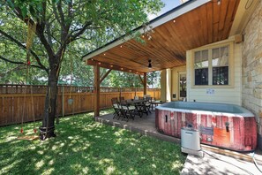 Een overdekt terras met een jacuzzi, houten terras en tuinmeubilair.