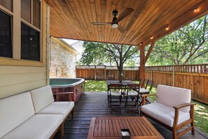 A covered outdoor patio with a hot tub, wooden deck, and seating area. - Hot Tub Retreat | Sleeps 12 | 10 mins to Dowtown (Austin)