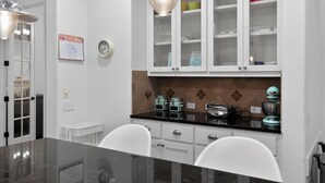 A kitchen with white cabinets, a black countertop, and a clock on the wall.