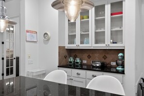 A kitchen with white cabinets, a black countertop, and a clock on the wall.