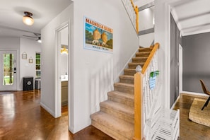 A staircase with a wooden handrail and beige carpeted steps, leading to a landing with a welcome sign. - Pet-Friendly Near Baylor & Magnolia|HotTub+Firepit (Waco)