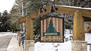 Un cartello di legno con il logo di un pino e il testo 'REDPINE Clubhouse', che indica un rifugio o una residenza.