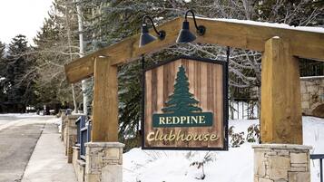 Een houten bord met een logo van een dennenboom en de tekst 'REDPINE Clubhouse', dat een lodge of verblijfplaats aangeeft.