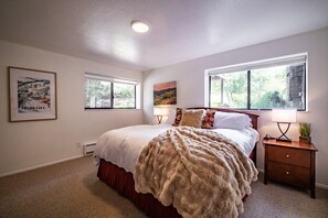 A bedroom with a large bed, two windows, a nightstand, and a lamp. - Park City Canyons Ski Chalet | Heated Pool/Hot Tub, Shuttle, 30- sec walk to Gondola (Park City)
