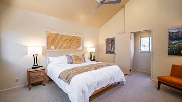 Een slaapkamer met een bed, twee nachtkastjes, een plafondventilator en kunstwerken aan de muur.