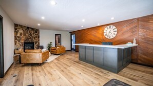 Un interno moderno caratterizzato da una parete in pietra, pannelli in legno, una reception, divani in pelle e un camino.