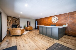 Ein modernes Interieur mit Steinwand, Holzvertäfelung, einer Rezeption, Ledersofas und einem Kamin.