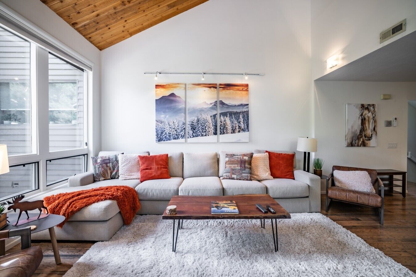 Een moderne woonkamer met een hoge plafond, een zithoek, een salontafel en kunstwerken aan de muur.