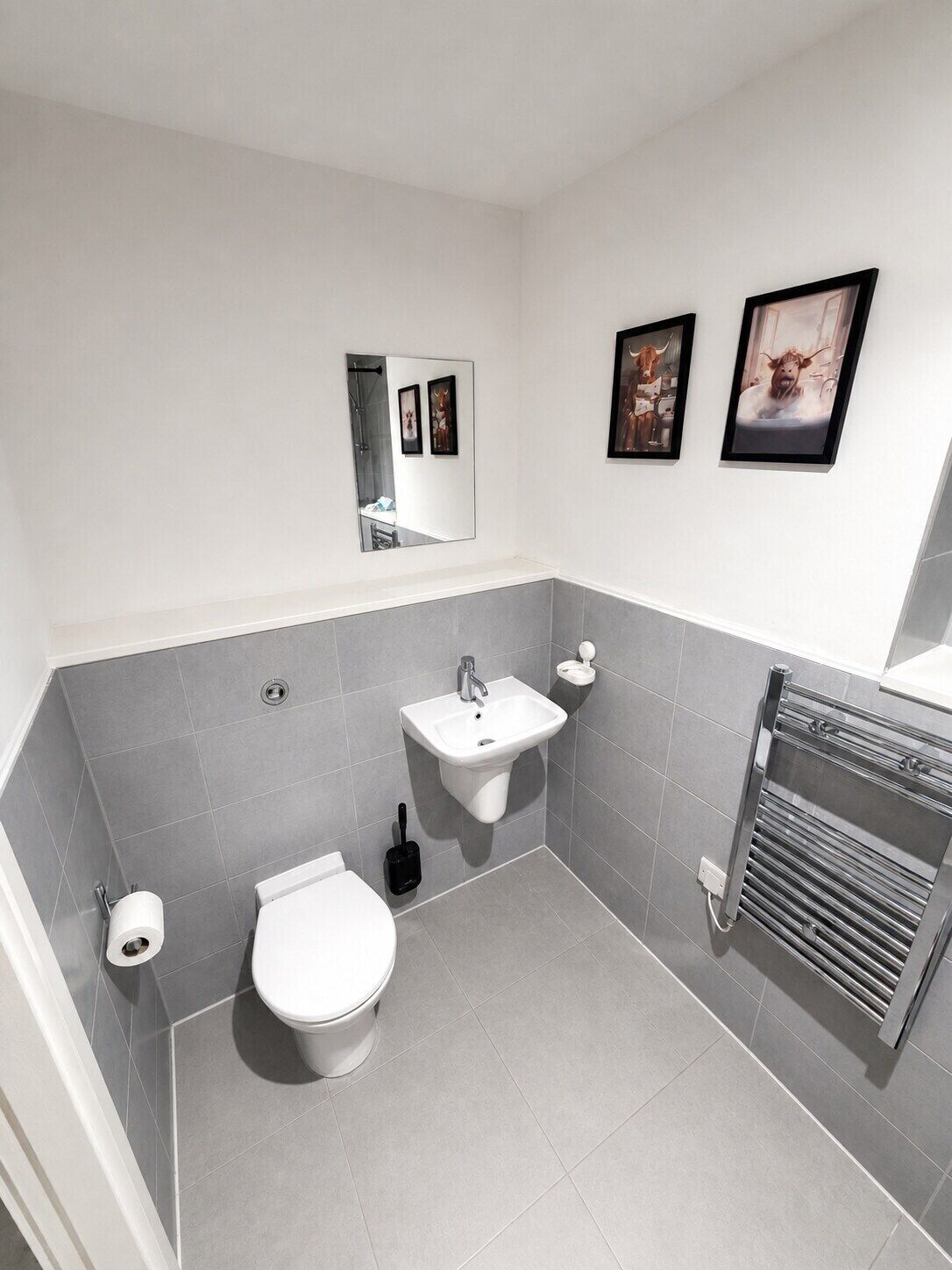 A modern bathroom with a toilet, sink, and towel rack.