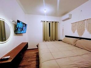 A bedroom with a bed, a TV mounted on the wall, a bedside table, and a wall-mounted air conditioning unit. - Casa Bambu, Playa del Carmen. (Playa del Carmen)