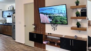 Cozinha moderna com televisão integrada, armários de madeira e painel decorativo na parede.