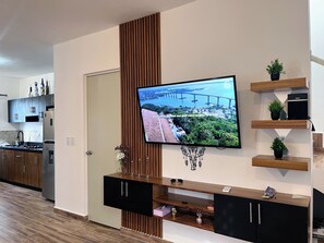 Eine moderne Küche mit integriertem Fernseher, Holzschränken und einer dekorativen Wandverkleidung.