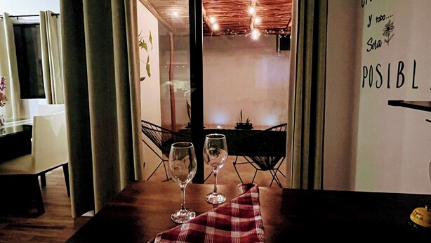 A dining area with a table set for two, two wine glasses, and a red and white checkered napkin.