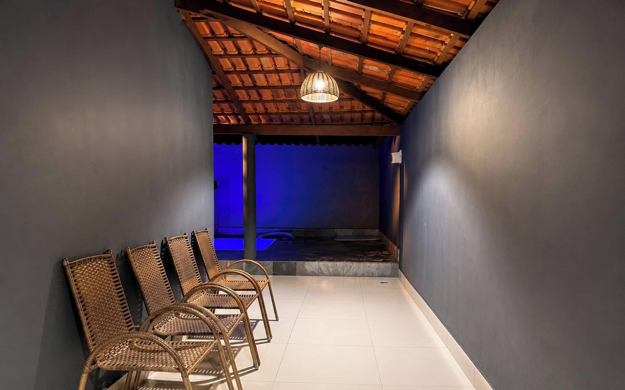 A corridor with a tiled floor, a wooden ceiling, and a blue-lit area at the end.