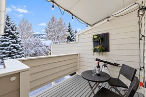 Un balcone con tavolo e sedie, un telescopio e una fioriera a parete con fiori.