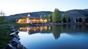 A lakeside lodge with a reflective pond, a wooden deck, and a mountain backdrop. - EagleVail Alpine Retreat | Pool, Golf & Pickleball (Avon)