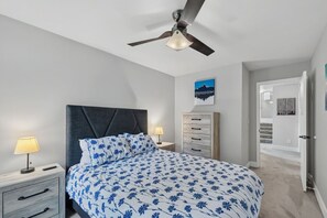 A bedroom with a bed, two bedside tables, a ceiling fan, a nightstand, a dresser, and a door leading to another room. - EagleVail Alpine Retreat | Pool, Golf & Pickleball (Avon)