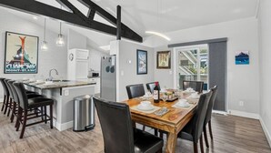 A modern kitchen with a dining area, featuring a wooden table set for six, black chairs, and a stainless steel refrigerator. - EagleVail Alpine Retreat | Pool, Golf & Pickleball (Avon)