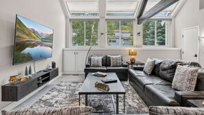 A modern living room with a large flat-screen TV, a sofa set, a coffee table, and a fireplace. - EagleVail Alpine Retreat | Pool, Golf & Pickleball (Avon)