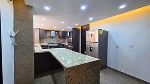 A modern kitchen with granite countertops, stainless steel appliances, recessed ceiling lights, and a built-in oven. - Residencia Élite Polanco | Corporate (Mexico City)