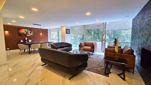 A modern interior with a sofa, chairs, a dining area, and large windows. - Residencia Élite Polanco | Corporate (Mexico City)