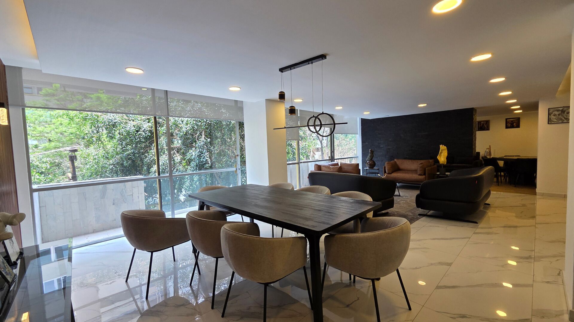 A modern interior with a dining area, seating, and a view through large windows.