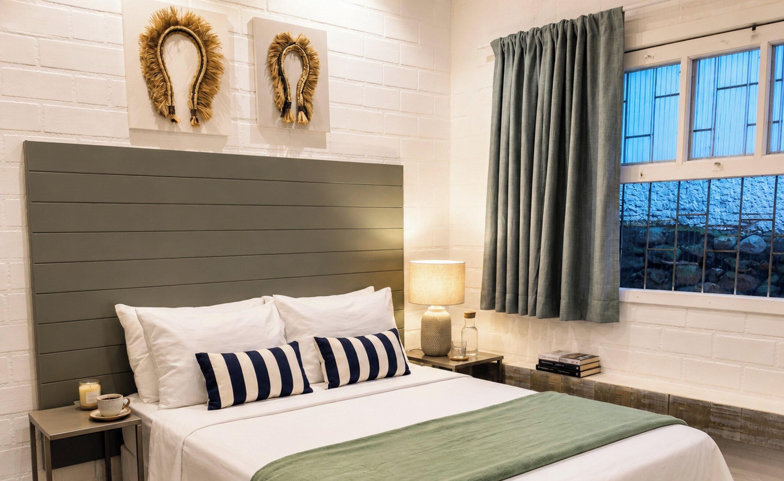 A hotel room with a bed, a nightstand, a lamp, and a window with curtains.