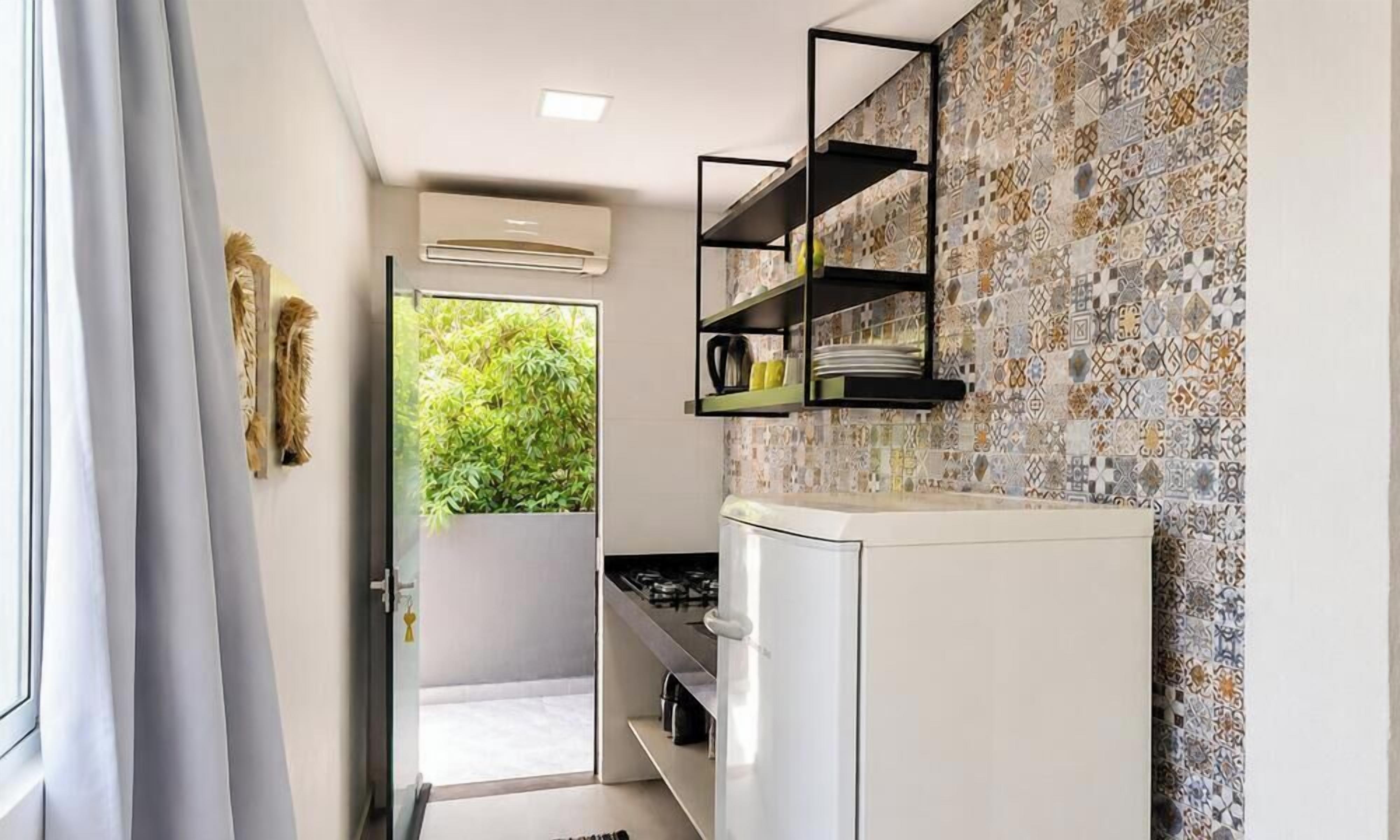Una cocina con un refrigerador blanco, un estante negro y un salpicadero con diseño.