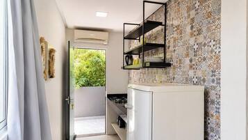 Una cocina con un refrigerador blanco, un estante negro y un salpicadero con diseño.