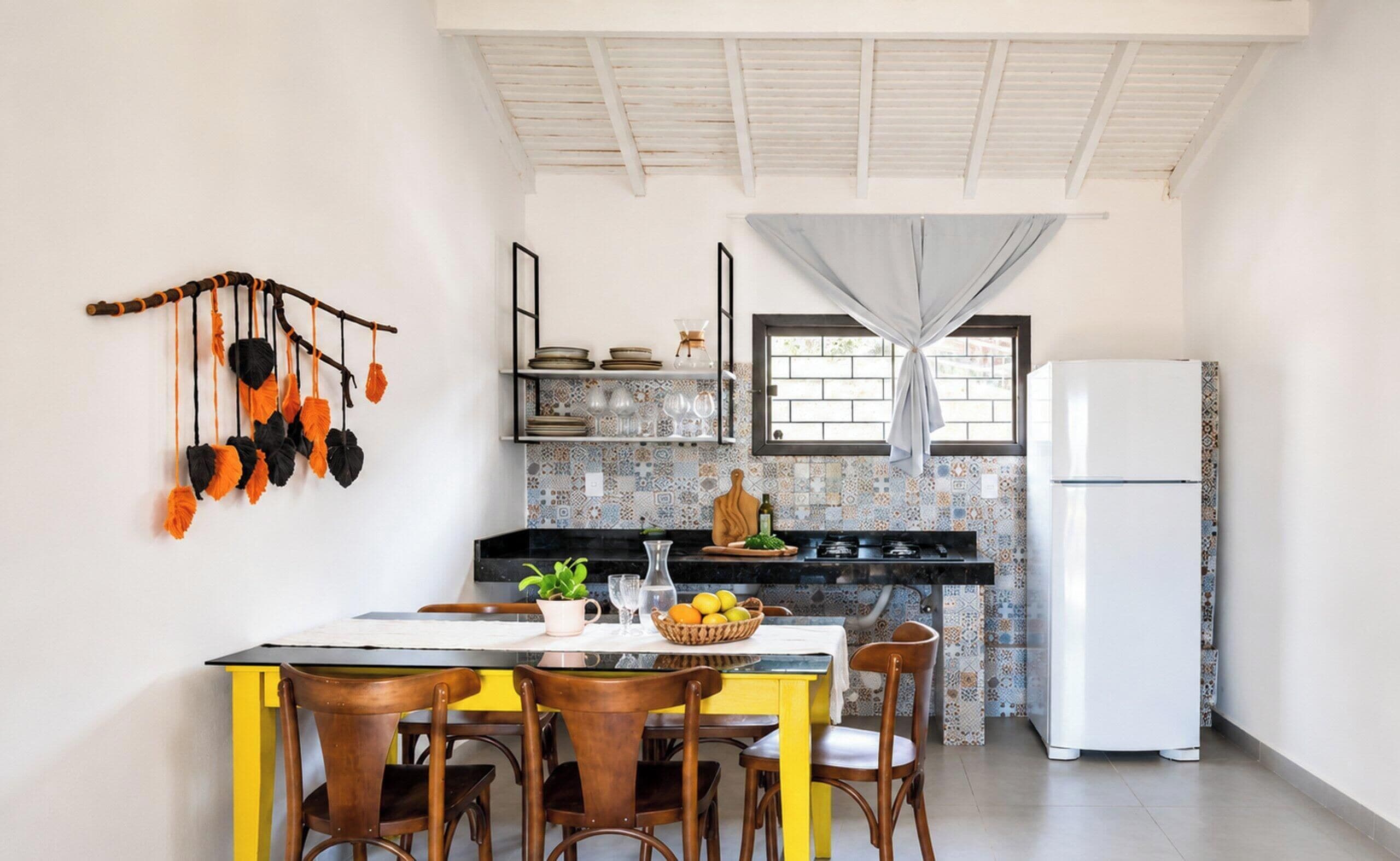 Cocina compacta con comedor, que cuenta con un salpicadero de azulejos, un refrigerador blanco y una planta decorativa colgante.