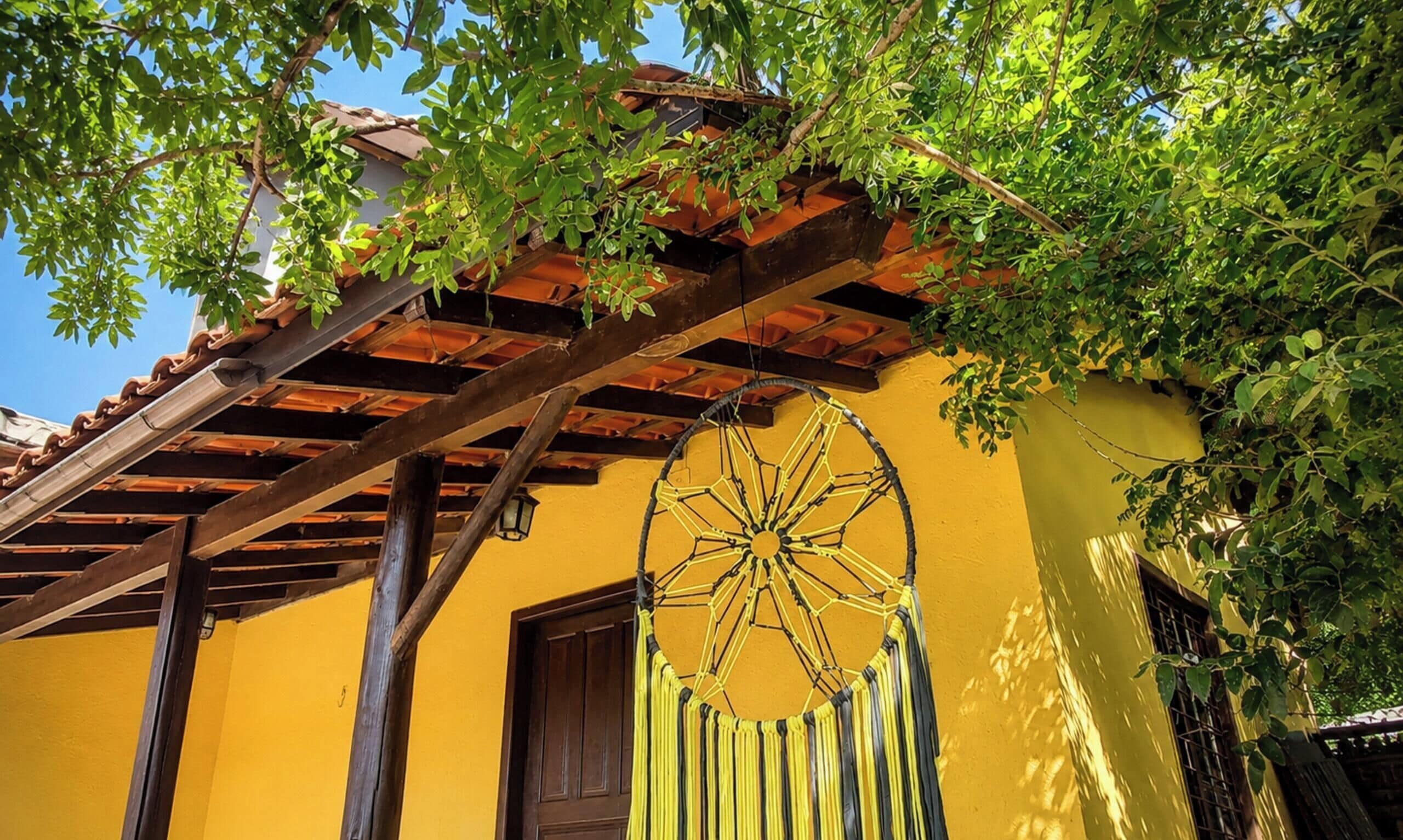 A yellow building with a wooden pergola and a large decorative wheel.
