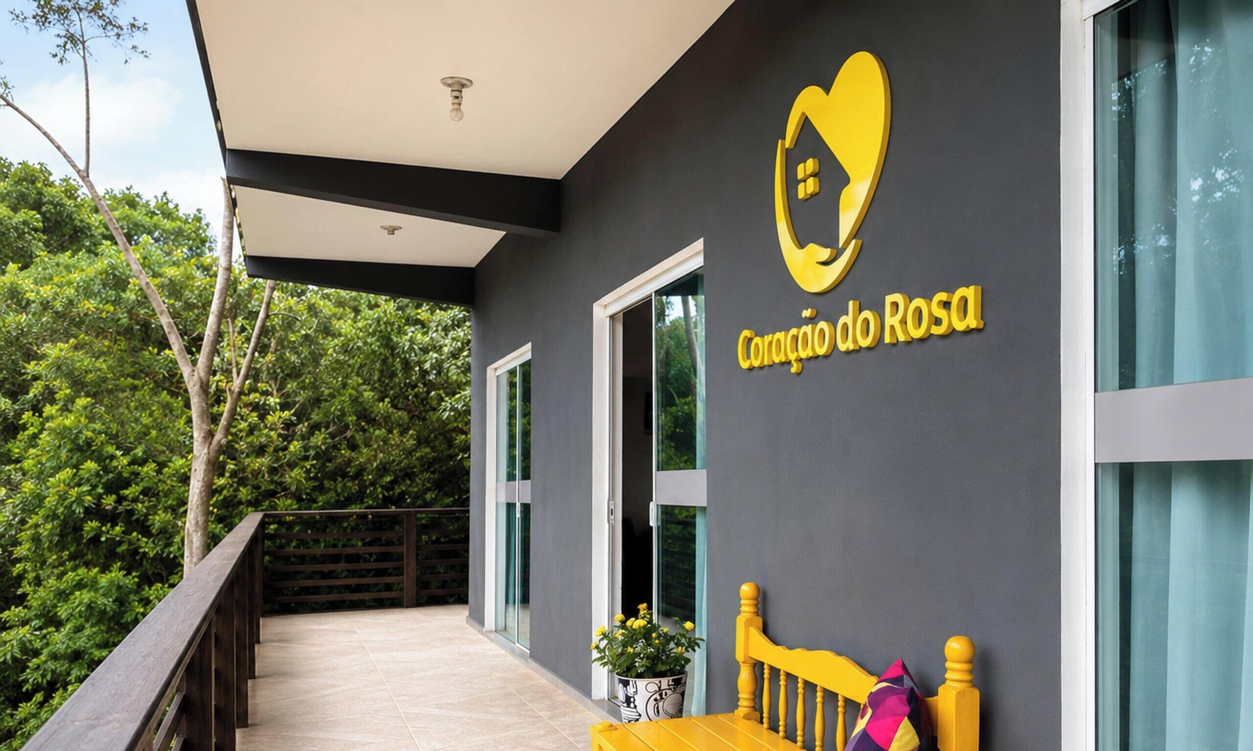 A modern building with a balcony, a logo with a heart and a house, and a sign that reads 'Coração do Rosal'.